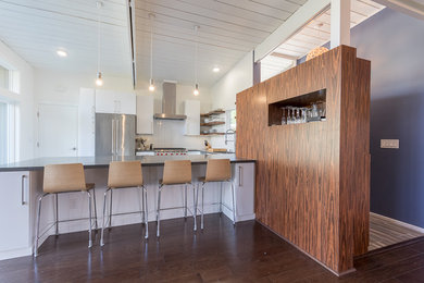 Large contemporary u-shaped open plan kitchen in San Francisco with a drop-in sink, flat-panel cabinets, yellow cabinets, white splashback, stainless steel appliances, dark hardwood floors and a peninsula.