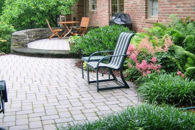 This is an example of a large transitional backyard full sun formal garden for summer in Philadelphia with a retaining wall and brick pavers.