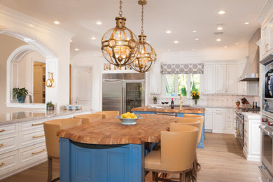 Inspiration for a large timeless l-shaped medium tone wood floor and brown floor eat-in kitchen remodel in Phoenix with a farmhouse sink, raised-panel cabinets, white cabinets, wood countertops, multicolored backsplash, colored appliances, two islands and brown countertops