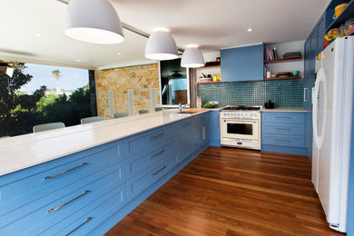 Inspiration for a mid-sized beach style u-shaped kitchen in Adelaide with an undermount sink, shaker cabinets, blue cabinets, quartz benchtops, blue splashback, ceramic splashback, stainless steel appliances, dark hardwood floors and a peninsula.