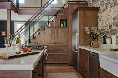 Inspiration for a country single-wall open plan kitchen in Philadelphia with a farmhouse sink, medium wood cabinets, stainless steel appliances, medium hardwood floors, with island and white benchtop.