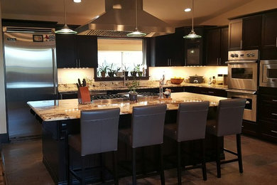 Inspiration for a large modern l-shaped ceramic tile and brown floor eat-in kitchen remodel in San Francisco with a double-bowl sink, flat-panel cabinets, black cabinets, granite countertops, beige backsplash, stone tile backsplash, stainless steel appliances, an island and beige countertops