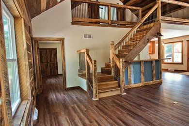 Example of a large mountain style open concept medium tone wood floor and brown floor living room design in Other with a bar, white walls, a standard fireplace and a stone fireplace