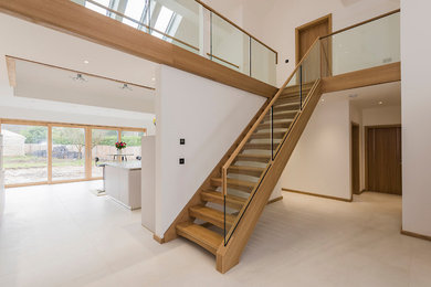 Imagen de escalera suspendida contemporánea extra grande sin contrahuella con escalones de madera y barandilla de vidrio