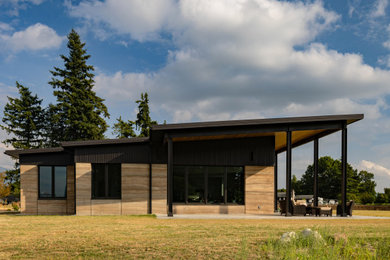 Mid-sized minimalist brown one-story mixed siding house exterior photo in Seattle with a shed roof, a metal roof and a black roof