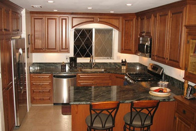 Inspiration for a small timeless u-shaped ceramic tile enclosed kitchen remodel in Sacramento with an undermount sink, raised-panel cabinets, dark wood cabinets, a peninsula, granite countertops and stainless steel appliances