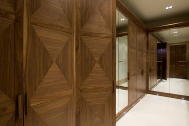Photo of a large traditional men's walk-in wardrobe in London with beaded inset cabinets and medium wood cabinets.