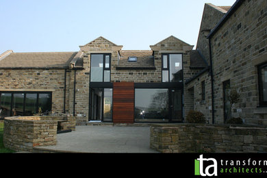 Contemporary Stone House Alterations With Large Black Glazing And Cladding