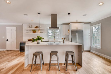 Inspiration for a contemporary galley medium tone wood floor and brown floor kitchen remodel in Baltimore with shaker cabinets, white cabinets, white backsplash, stainless steel appliances, an island and white countertops