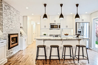 Transitional medium tone wood floor kitchen photo with an undermount sink, shaker cabinets, beige backsplash, porcelain backsplash, stainless steel appliances and an island