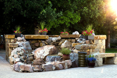 This is an example of a mid-sized tropical backyard partial sun formal garden for spring in Boise with brick pavers and a water feature.