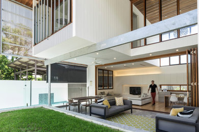 Expansive contemporary backyard deck in Brisbane with a water feature and a roof extension.