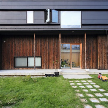 芝生の庭とヒノキ板貼り壁とガルバリウム鋼板壁のコントラスト