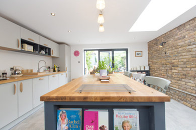 Inspiration for a large contemporary single-wall ceramic tile eat-in kitchen remodel in Surrey with a drop-in sink, flat-panel cabinets, white cabinets, laminate countertops, white backsplash, an island and brown countertops