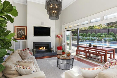 This is an example of a mid-sized open concept living room in Sydney with blue walls, carpet, a standard fireplace, a plaster fireplace surround, a freestanding tv and beige floor.
