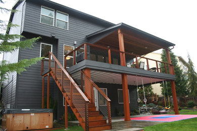Large minimalist backyard deck photo in Portland with a roof extension