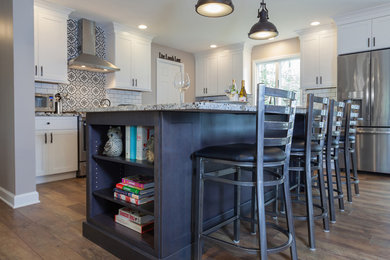 This is an example of a mid-sized eclectic l-shaped eat-in kitchen in Philadelphia with an undermount sink, shaker cabinets, grey cabinets, granite benchtops, white splashback, subway tile splashback, stainless steel appliances, laminate floors, with island, brown floor and white benchtop.
