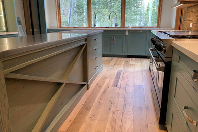 Example of a mid-sized eclectic u-shaped medium tone wood floor, brown floor and exposed beam eat-in kitchen design in Denver with an undermount sink, shaker cabinets, green cabinets, an island and white countertops