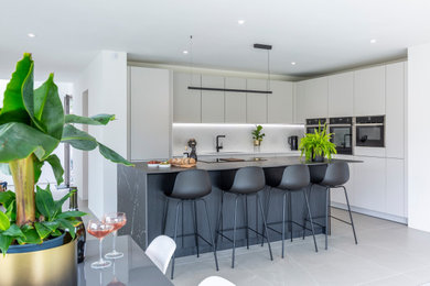 Photo of a large contemporary grey and white single-wall open plan kitchen in Cheshire with grey splashback, an island, grey floors and grey worktops.