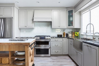 Enclosed kitchen - large modern u-shaped light wood floor and brown floor enclosed kitchen idea in Richmond with a farmhouse sink, raised-panel cabinets, gray cabinets, quartz countertops, blue backsplash, glass tile backsplash, stainless steel appliances and an island