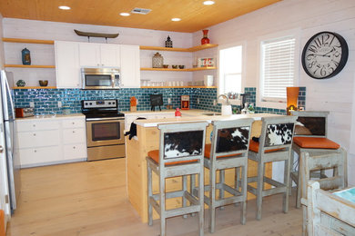 Inspiration for a mid-sized coastal u-shaped light wood floor and beige floor enclosed kitchen remodel in Austin with an undermount sink, flat-panel cabinets, white cabinets, solid surface countertops, blue backsplash, ceramic backsplash, stainless steel appliances and no island