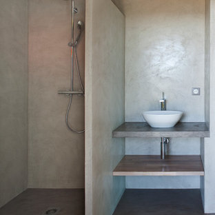 Réalisation d'une salle d'eau design avec une vasque, un placard sans porte, des portes de placard en bois brun, un plan de toilette en bois, un mur gris, béton au sol et une douche à l'italienne.