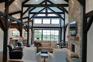 Large country open concept dark wood floor, brown floor, exposed beam and wood wall living room photo in Austin with white walls, a standard fireplace, a stacked stone fireplace and a wall-mounted tv