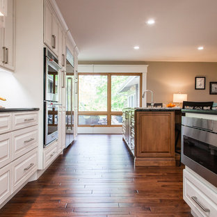 Large transitional kitchen pantry inspiration - Inspiration for a large transitional galley medium tone wood floor and brown floor kitchen pantry remodel in Wichita with an undermount sink, raised-panel cabinets, white cabinets, quartzite countertops, multicolored backsplash, limestone backsplash, stainless steel appliances and an island