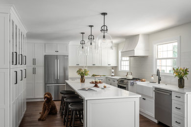 Inspiration for a large modern u-shaped dark wood floor and brown floor eat-in kitchen remodel in Philadelphia with a farmhouse sink, shaker cabinets, white cabinets, quartz countertops, white backsplash, ceramic backsplash, stainless steel appliances, an island and white countertops