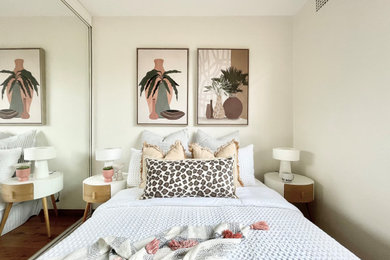Inspiration for a small guest bedroom in Sydney with beige walls, medium hardwood floors and brown floor.
