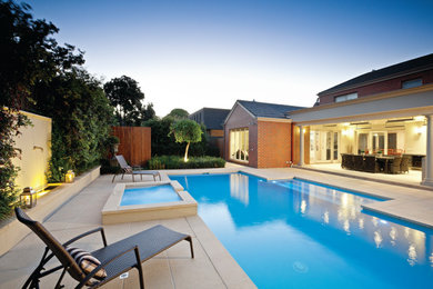 Design ideas for a large contemporary backyard custom-shaped pool in Melbourne with a hot tub and natural stone pavers.