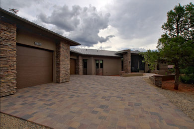 This is an example of an arts and crafts one-storey stucco brown house exterior in Other with a hip roof and a metal roof.