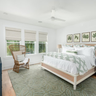 Cette image montre une grande chambre parentale ethnique avec un mur blanc, un sol en bois clair et un sol vert.