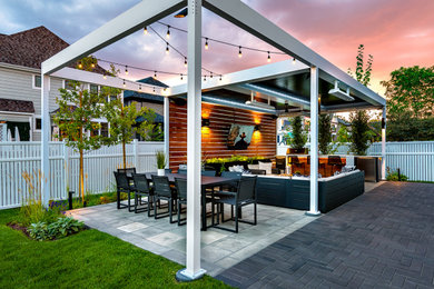 Example of a mid-sized trendy backyard stone patio kitchen design in Chicago with a pergola