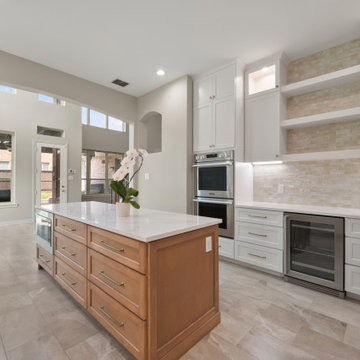 Wide-Angle Open Kitchen View Showing Island, Wall Ovens, and Living Area