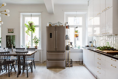 Photo of an eclectic eat-in kitchen in Stockholm with flat-panel cabinets and no island.