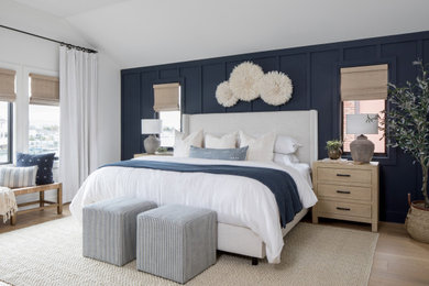 Ejemplo de dormitorio principal costero de tamaño medio con paredes azules, suelo de madera en tonos medios y panelado