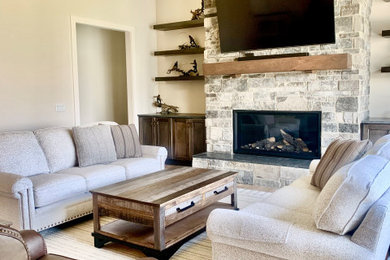 Example of a farmhouse open concept vinyl floor, brown floor and vaulted ceiling living room design in Grand Rapids with a standard fireplace, a stone fireplace and a wall-mounted tv