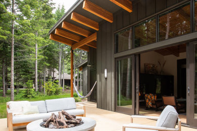 Inspiration for a large modern backyard concrete patio remodel in Seattle with a fire pit and a roof extension