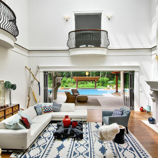 Großes, Offenes, Repräsentatives, Fernseherloses Mediterranes Wohnzimmer mit weißer Wandfarbe, braunem Holzboden, Kamin und gefliestem Kaminsims in New York