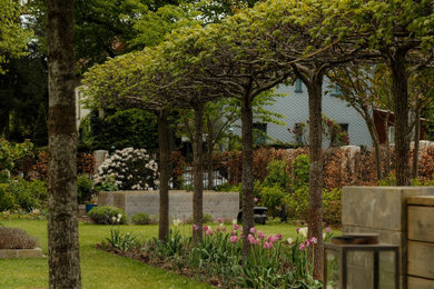 Geometrischer, Großer Moderner Garten im Frühling, hinter dem Haus mit Blumenbeet und direkter Sonneneinstrahlung in Berlin