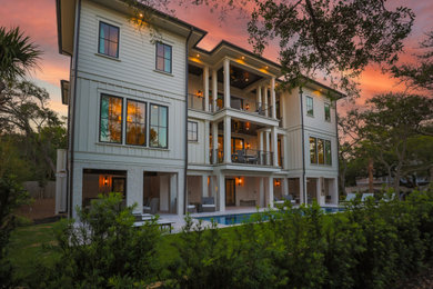 Large transitional white three-story concrete fiberboard and board and batten house exterior idea in Other with a hip roof, a metal roof and a brown roof