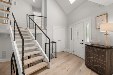 Photo of a modern front door in DC Metro with white walls, light hardwood floors, a single front door and a white front door.