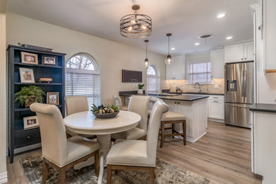 Eat-in kitchen - transitional galley vinyl floor and beige floor eat-in kitchen idea in Other with a double-bowl sink, recessed-panel cabinets, white cabinets, granite countertops, beige backsplash, travertine backsplash, stainless steel appliances, a peninsula and black countertops