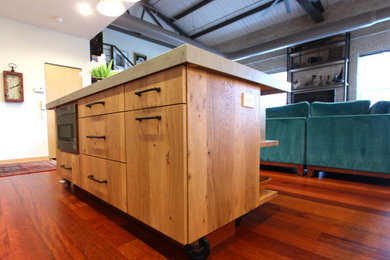 Urban dark wood floor and red floor kitchen photo in Other with flat-panel cabinets, light wood cabinets, concrete countertops, stainless steel appliances, an island and gray countertops