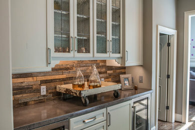 Example of a mid-sized country l-shaped dark wood floor and brown floor enclosed kitchen design in Other with a farmhouse sink, shaker cabinets, gray cabinets, granite countertops, gray backsplash, subway tile backsplash, stainless steel appliances and an island