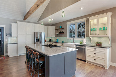 Large transitional l-shaped medium tone wood floor eat-in kitchen photo in Other with a farmhouse sink, white cabinets, granite countertops, glass tile backsplash, an island, stainless steel appliances, green backsplash and shaker cabinets