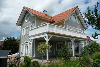 Foto della villa ampia grigia tropicale a due piani con rivestimento in legno, tetto a capanna e copertura in tegole