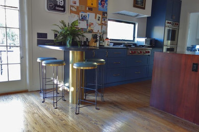 Foto di una cucina design chiusa e di medie dimensioni con ante in stile shaker, ante blu, top in superficie solida, elettrodomestici in acciaio inossidabile, parquet chiaro, pavimento beige e paraspruzzi a finestra