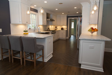 Eat-in kitchen - mid-sized transitional galley porcelain tile eat-in kitchen idea in New York with a farmhouse sink, recessed-panel cabinets, white cabinets, quartzite countertops, white backsplash, subway tile backsplash, stainless steel appliances and a peninsula